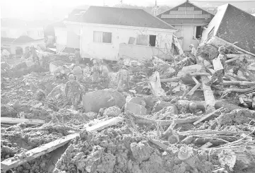  ??  ?? Rescue workers and Japan Self-Defence Forces soldiers search for missing people at a landslide site caused by heavy rain in Kumano Town, Hiroshima Prefecture. — Reuters photo