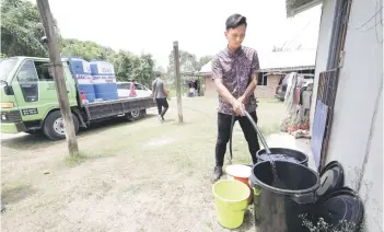  ?? — Bernama photo ?? A Papar Member of Parliament Office worker helping residents of Kampung Tampasak Papar fill up water on Thursday.