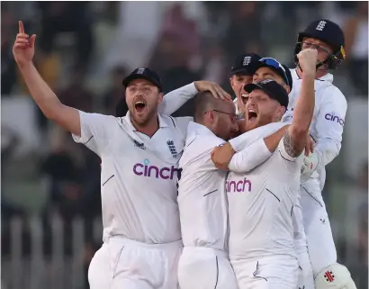  ?? ?? Jack Leach, second left, is engulfed by his team- mates after taking the final Pakistani wicket