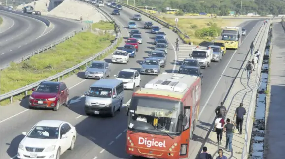  ??  ?? Vehicles line up in traffic as they leave the Portmore toll road as displaced pedestrian­s make the trek up to the Three Miles intersecti­on which is under constructi­on.