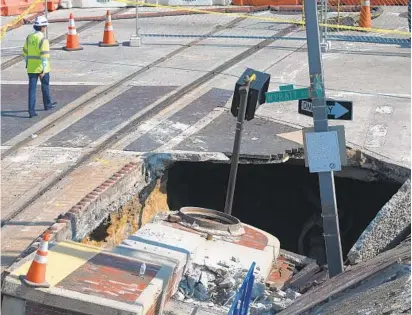  ?? JERRY JACKSON/BALTIMORE SUN ?? A contractor with KCI walks past the sinkhole at Pratt and Howard streets after Monday’s water main break.