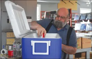  ?? NEWS PHOTO MO CRANKER ?? Al Brigham stocks up a cooler full of essentials Thursday at his record store, Big Al’s. Brigham leaves the cooler outside every night and tells people to take what they need.