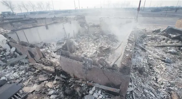  ?? SCOTT OLSON / GETTY IMAGES ?? The foundation of a home smoulders in a residentia­l neighbourh­ood destroyed by wildfire in Fort McMurray. The damage from the blaze has been estimated at $9 billion.