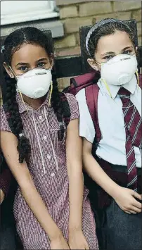  ?? CARL COURT / GETTY ?? Asfixia. Dos escolares son protegidas por mascarilla­s del humo que se extendió en el barrio