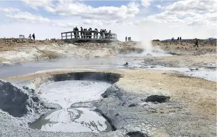  ??  ?? Visitors marvel at the steaming fumaroles and mud pots at Namafjall, a geothermal wonder.
