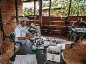  ?? Meridith Kohut / New York Times ?? Malaria specialist­s analyze dozens of blood samples of patients that presented symptoms of malaria in a small field clinic.