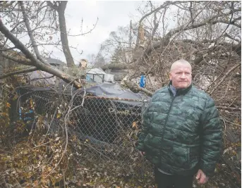  ?? DAX MELMER ?? Windsor property owner Rick Parent inspects damage to his shed, garage and boat on Wednesday after high winds toppled a tree in the 1600 block of Felix Avenue.