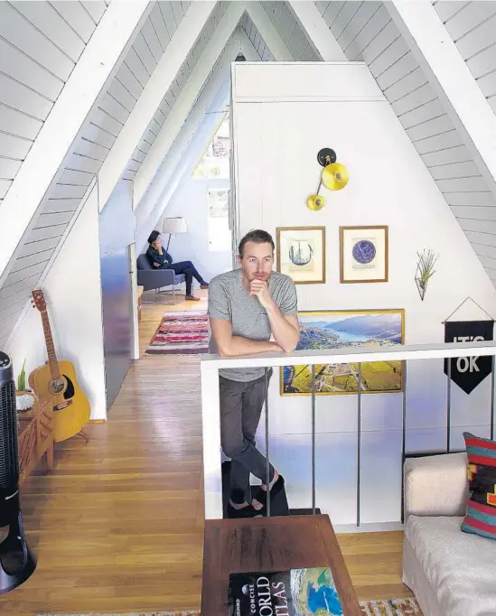  ?? Kirk McKoy Los Angeles Times ?? JAKE HURWITZ thinks atop the stairs while his fiancée Jillian Vogel takes a call in the second floor loft of their updated A-frame cabin in Mount Washington.