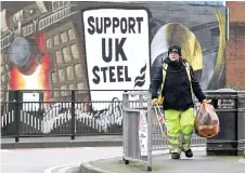  ?? ?? A rubbish collector walks past a mural in support of the UK Steel.