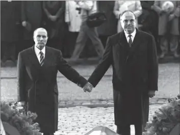  ??  ?? The Sept. 22, 1984 file photo shows then French President Francois Mitterrand and German Chancellor Helmut Kohl standing hand-in-hand as they listen to their respective national anthems during a French-German reconcilia­tion ceremony outside the...