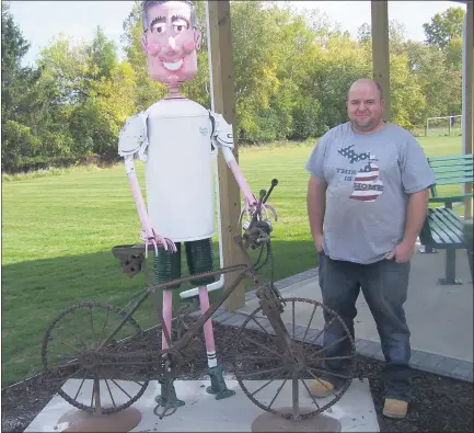  ?? GREG NELSON — MORNING SUN ?? Justin Ladoux stands next to the sculpture he designed of the late Scott Sheldon, who passed away earlier this year. His wife Sandy and other family members and friends had the sculpture, as well as a pavilion, picnic tables and benches built at the Fred Meijer Heartland Trail trailhead on Charles Avenue in Alma in Scott’smemory.