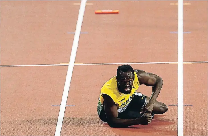  ??  ?? Derrumbado sobre el tartán, Usain Bolt observa el sorprenden­te desenlace del relevo corto: Gran Bretaña derrotó a Estados Unidos