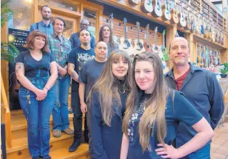  ?? EDDIE MOORE/JOURNAL ?? Rand Cook, right, his wife, Cindy, and their daughter, Jayda, with the staff of The Candyman Strings and Things store on St. Michael’s Drive. The store is celebratin­g its 50th anniversar­y this year.