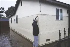  ?? DENIS POROY/AP ?? JUAN GONZALES GESTURES TO THE WATERLINE of a flooded home during a rain storm on Monday in San Diego.