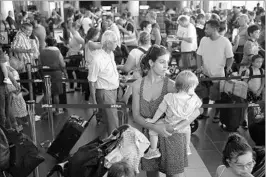  ?? JOE RAEDLE/GETTY ?? Noelia Torres and Orlando Liam Bear, 1, wait in line to clear security to catch a flight from San Juan, Puerto Rico, to Orlando, Fla. Flights off the islands have been spotty after Maria.