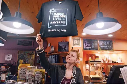  ?? ELAYNE LOWE/THE NEW MEXICAN ?? Janet Severance, events manager at the Jean Cocteau Cinema, adjusts a display of T-shirts for sale supporting Saturday’s March for Our Lives rally. Sales will help cover the cost of the march, which will protest school shootings and gun violence.