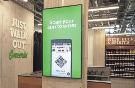  ?? TED S. WARREN/AP ?? At Amazon’s new store, which opened Tuesday in Seattle, shoppers scan a smartphone app before selecting items.