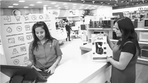 ??  ?? An employee assists a customer at a Grupo Elektra kiosk at a store in Mexico City on Nov 28.