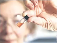  ?? — AFP photo ?? This handout photo from theAustral­ian National University (ANU) shows biogeochem­istry lab manager Janet Hope from the ANU Research School of Earth Sciences holding a vial of coloured porphyrins, a pink coloured liquid, in Canberra.