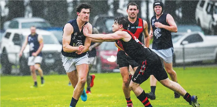  ?? Photograph Craig Johnson ?? Catani’s Coby Podd fires a handpass as Nima Darnum’s Garry Hallam tries to put him off balance as the rain pours down at Darnum on Saturday.