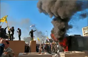  ?? Khalid Mohammed/Associated Press ?? Protesters burn property Tuesday in front of the U.S. Embassy compound in the Iraqi capital of Baghdad.