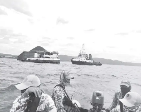  ?? PHOTO COURTESY OF PCG ?? PHILIPPINE Coast Guard personnel keep a close watch on tugboat MT Clyde and barge Claudia, which both came from Indonesia and briefly docked at the Butuan Port, after most of the crewmen of both vessels tested positive for the virus.