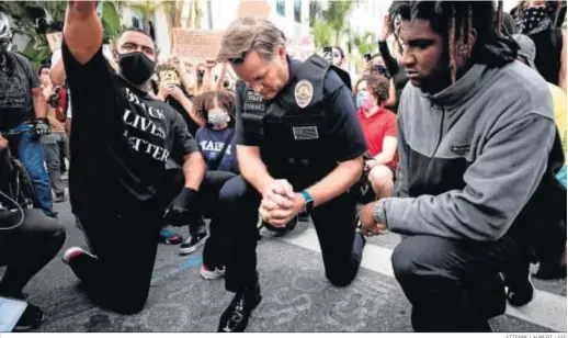  ?? ETIENNE LAURENT / EFE ?? Cory Palka (c), comandante del Departamen­to de Policía de Los Ángeles, se arrodilla con manifestan­tes que protestan contra la violencia racial.