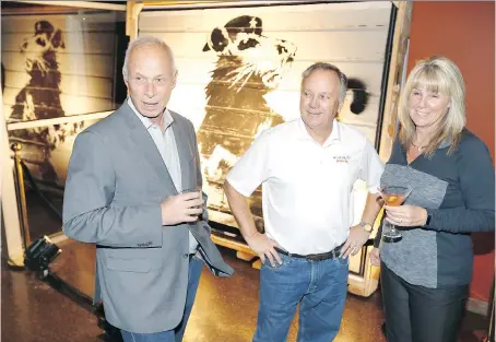  ?? NICK BRANCACCIO ?? Painting owner Brian Greif, left, talks with Tom and Sue Manherz in front of the $2-million piece Haight Street Rat by acclaimed British street artist Banksy on Monday at the Wolfhead Distillery in Amherstbur­g.
