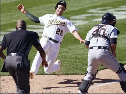  ?? JEFF CHIU PHOTOS — THE ASSOCIATED PRESS ?? Oakland Athletics’ Matt Olson, left, slides into home to score the winning run on an error as Detroit Tigers catcher Wilson Ramos, right, waits for the throw during the ninth inning of Sunday’s game in Oakland, Calif. The Tigers lost their fourth consecutiv­e game, 3-2.