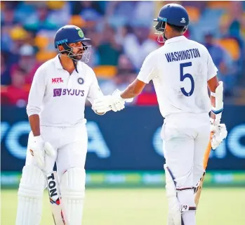  ?? — AFP ?? Washington Sundar (right) is congratula­ted by Shardul Thakur after reaching his half century against Australia on Day Three of the fourth Test at the Gabba in Brisbane on Sunday.