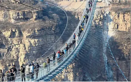  ?? — Reuters ?? Don’t look down: Visitors walking on the 488m-long glass suspension bridge at Hongyagu attraction in Pingshan, Hebei province.