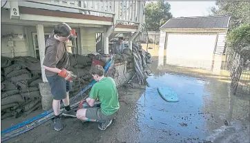  ?? FILE PHOTO ?? Eric Heckman, bottom background, and his sons, Owen, 17, left, and Ethan, 14, right, start the water pump to drain the flooded back yard of their house that rests near the bank of the Coyote Creek in San Jose in 2017.