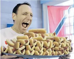  ?? RICHARD DREW/AP ?? Current men's champion Joey Chestnut, of San Jose, Calif., holds a tray of hot dogs during the weigh-in for the 2017 Nathan’s Hot Dog Eating Contest. You could be his competitio­n this year, if you have the guts to qualify in Miami.