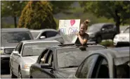  ??  ?? Stella Wright, 12, of Exeter, holds a sign out of the sunroof of a car that reads “We love you Msgr. Treston” as they wait in a line of other vehicles during a drive-thru tribute to Monsignor James Treston at St. Catharine of Siena Catholic Church in Exeter Township on the afternoon of May 14.