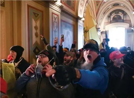  ?? Getty iMages file pHotos ?? SEEKING JUSTICE: Supporters of former President Donald Trump protest inside the U.S. Capitol on Jan. 6 in Washington, D.C. Below, a supporter sits inside the office of Speaker of the House Nancy Pelosi during the riots.