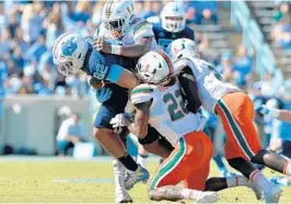  ?? GRANT HALVERSON/GETTY IMAGES ?? Zach McCloud and Sheldrick Redwine (22) of the Miami Hurricanes are in on the tackle of North Carolina’s Brandon Fritts.