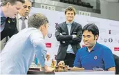 ?? Partiím Sergeje Karjakina (vlevo) pozorně přihlížel i Magnus Carlsen a vždy držel palce Karjakinov­ým soupeřům. Na prvním snímku je Nor zamračený, protože Rus svého amerického soupeře přehrává. Na tom druhém se usmívá, protože Karjakin si nechal dát od Hik ??