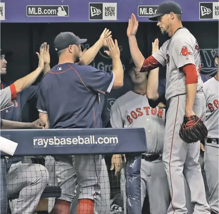  ?? AP PHOTO ?? WINNING FORM: Clay Buchholz gets a warm welcome in the dugout after leaving in the seventh inning of the Red Sox’ 2-1 victory against the Rays last night in St. Petersburg, Fla.