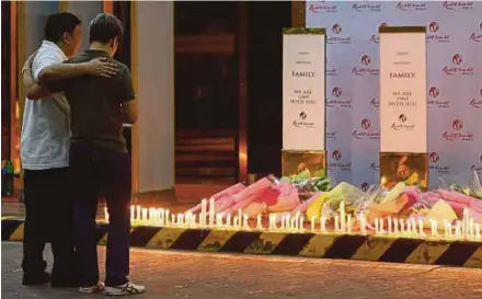  ?? EPA PIC ?? People looking at the flowers and candles in tribute to shooting victims at the entrance of the Resorts World Manila hotel and casino complex in Pasay City on Friday.