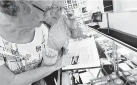  ?? BRIAN KRISTA/BALTIMORE SUN MEDIA GROUP ?? Libby and Marvin Fox find a picture of Libby riding a parade float in a past Maryland State Fair. The Parkville couple met at a fair parade in 1959 and married three years later.