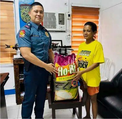  ?? PHOTOGRAPH FOR DAILY TRIBUNE BY MAR T SUPNAD ?? A WIFE of a person deprived of liberty in Limay, Bataan receives a sack of rice from a police officer in line with the local government’s thrust to provide aid to the families of inmates.