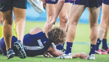  ?? Picture: AAP ?? DOWN AND OUT: Nat Fyfe is surrounded by concerned teammates after the knock.