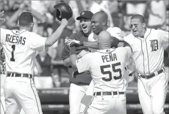  ?? PAUL SANCYA/ THE ASSOCIATED PRESS ?? Torii Hunter, top center, is greeted by Tigers teammates after hitting a three-run homer in the ninth inning to give Detroit a 7-6 home win over the Oakland Athletics on Thursday. The Tigers rallied with four runs in the inning.