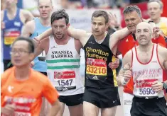  ?? PICTURE: ADRIAN DENNIS ?? Matthew Rees, left, of Swansea Harriers helps David Wyeth, centre, of Chorlton Runners, reach the finish line during the London marathon last year