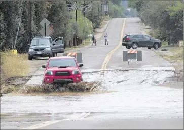  ?? Sean M. Haffey
San Diego Union- Tribune ?? RAMONA in San Diego County was hit very hard, with rainfall causing flooding throughout the town. Local motorists proceed carefully through the water on Magnolia Street near California 78.