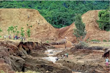  ?? AP ?? People gather in front of the broken banks of the Patel dam near Solai, in Kenya’s Rift Valley.