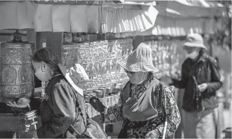  ?? MARK SCHIEFELBE­IN/AP ?? People spin prayer wheels June 1 outside the Potala Palace in Lhasa in western China’s Tibet Autonomous Region.