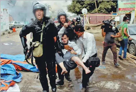  ?? HASSAN MOHAMED / AGENCE FRANCE-PRESSE ?? Egyptian police carry a wounded protester during clashes as security forces try to disperse protest camps set up by supporters of ousted president Mohammed Morsi in Cairo on Wednesday.