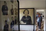  ?? HENG SINITH — THE ASSOCIATED PRESS ?? In this file photo, tourists view portraits of victims executed by the Khmer Rouge regime at the Tuol Sleng Genocide Museum in Phnom Penh, Cambodia.