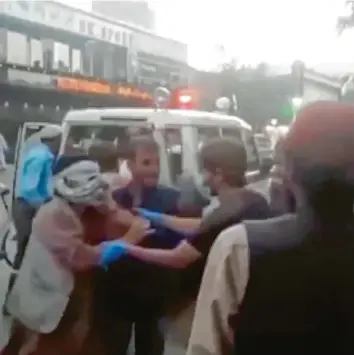  ?? Foto: Uncredited, A·vaka News Agency, dpa ?? Menschen kümmern sich in diesem Bild aus einem Video um einen Verletzten nach den Anschlägen in Kabul. Dutzende Menschen sind bei dem Attentat getötet worden, darunter alleine zwölf US‰Soldaten.